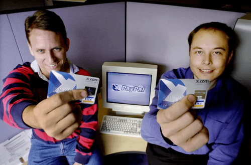 Elon Musk and Peter Thiel in front of a computer with a x.com credit hard in their hands
